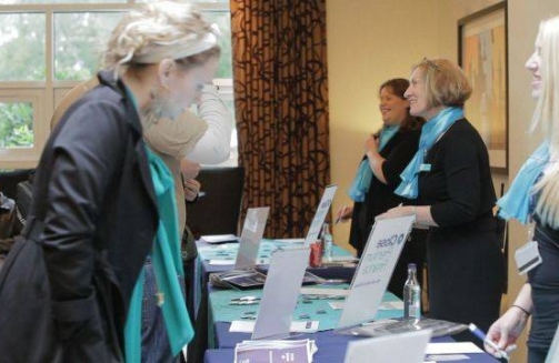 KDM Events - Conference Management Company - Three ladies standing behind a conference welcome check in desk'